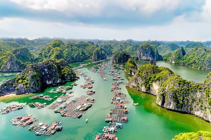 Hình ảnh minh họa một ngôi làng chài yên bình nằm giữa các dãy núi đá vôi hùng vĩ với những ngôi nhà nổi và thuyền thúng nằm san sát trên mặt nước.